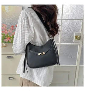 Detail of a black leather bucket bag featuring a golden heart interlocking buckle and strap