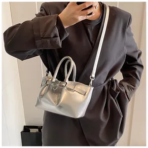 Silver bucket bag with buckle detail shown as a crossbody on a stylish grey blazer