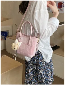 Pink fabric tote bag with teddy bear charm and adjustable strap worn by a female model