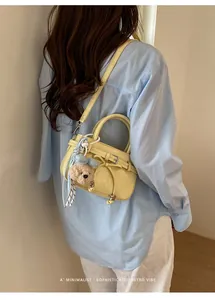 Close-up of yellow minimalist mini handbag with bow detail and cute bear charm