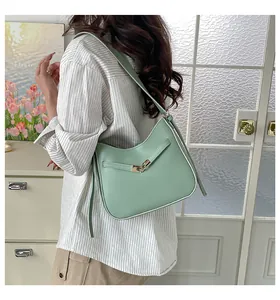Detail view of mint green leather bucket bag with fringe and metal lock on a model