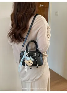 Detail of a mini black patent leather bag with a cute teddy bear charm and bow accent
