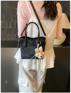 Detail of black checkered denim shoulder bag with a cute puppy plush charm