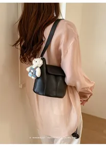 Model wearing a black leather bucket bag from behind with a cute white bear charm detail