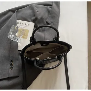 Dettaglio della borsa a secchiello nera intrecciata con chiusura magnetica e fodera morbida