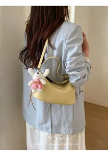 Detail of light yellow retro crossbody bag with plush doll and elegant tassel charm