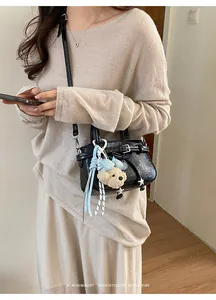 Detail of black retro small square bag with cute plush bear charm and buckle strap