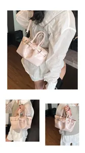 Detail of glossy pink bucket bag with decorative buckle and detachable strap