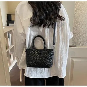 Dettaglio della borsa a secchiello intrecciata nera indossata da una modella chic