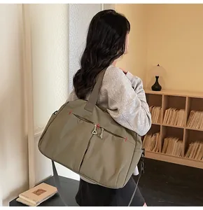 Olive green travel duffel bag with multi-pocket design shown on model in soft indoor light
