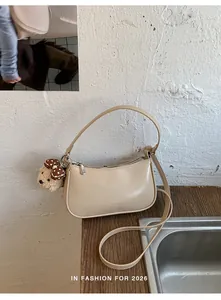 Detail of beige faux leather shoulder bag with plush teddy bear charm and dual straps