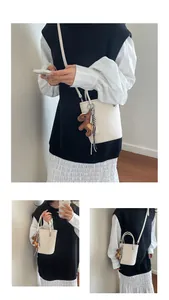Detail of cream bucket bag with lychee texture leather and a small horse charm