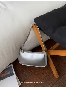 Detail of silver patent leather crescent bag with logo on a modern lifestyle background