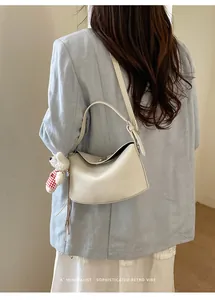 Close-up of cream pebble leather handbag with a cute teddy bear charm on a female model