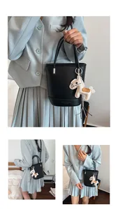 Detail of black leather bucket bag with silver hardware and a cream horse-shaped charm