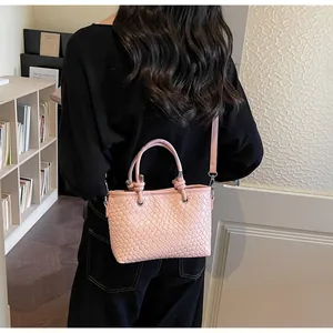 Vista posteriore di una modella con la borsa a secchiello rosa intrecciata a tracolla
