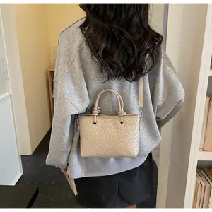 Dettaglio borsa a secchiello intrecciata beige con manici lisci e anelli d'argento