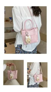 Detailed view of pink tweed handbag with detachable strap and teddy bear charm accessory