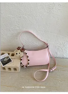 Detail of pink crossbody bag with teddy bear charm and colorful bead accents