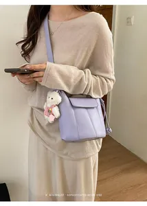 Detail of light purple bucket bag with plush bear charm and thin shoulder strap