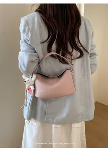 Close-up of pink leather shoulder bag with a cute plush bear charm on the handle