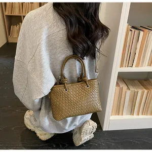 Dettagli della borsa a secchiello in pelle intrecciata marrone con tracolla a nodo