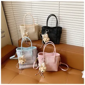 Detail of four colorful bucket bags with plush bear charms and textured canvas material