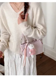 Detail der hellvioletten Beuteltasche mit Plüschbären-Anhänger und Knoten-Schultergurt