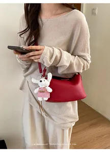 Detail view of red lychee textured leather handbag with a cute plush rabbit charm