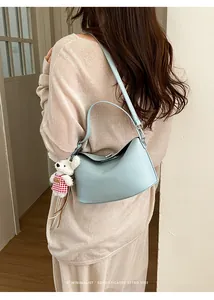Detail of light blue leather Lindy bag with a cute bear charm and metal buckle closure