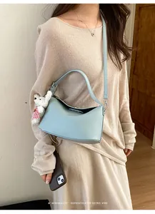 Detail of light blue hobo bag with lychee texture and cute white teddy bear charm