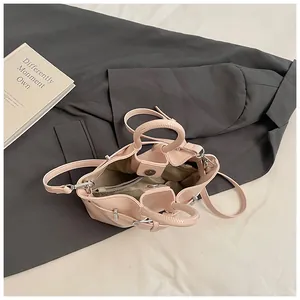 Chic pink bucket bag with leather handles and detachable strap on a premium background