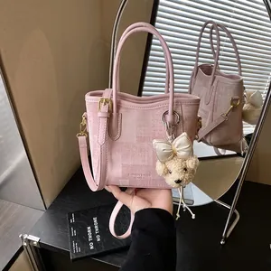 Pink textured canvas tote bag with bear charm and leather handles in a mirror view