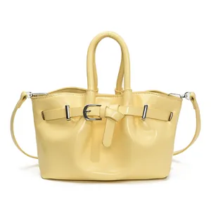 Bright yellow patent leather bucket bag with dual handles and metal buckle strap