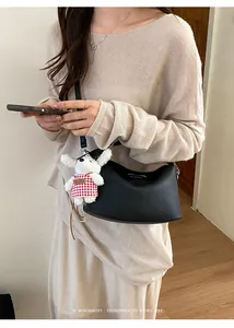 Detail showing black lychee leather crossbody bag with a cute plush dog pendant