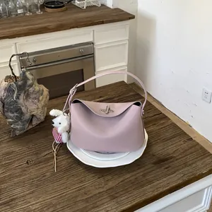 Detail of pink lychee grain leather handbag with cute plush dog charm on wooden table