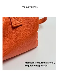 Detail of orange lychee textured leather tote featuring reinforced cross-stitch on the handle