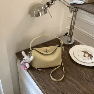 Detailed view of yellow litchi grain leather bag with metal lock on a vintage desk