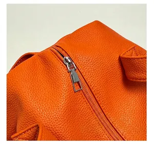 Detailed macro view of silver metal zipper and textured orange lychee leather on bag