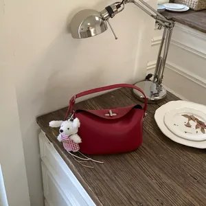 Detailed view of red leather crossbody bag with pebble texture and cute bunny charm