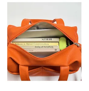 Top view of bright orange pebbled leather tote showing spacious interior for books