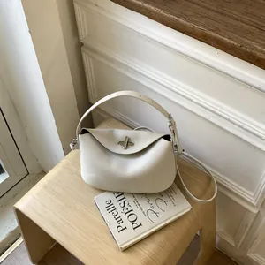 Elegant off-white pebbled leather handbag with turn-lock closure on wooden stool