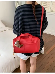 Detail of red pebbled leather tote bag with a brown plush pony charm and shoulder strap