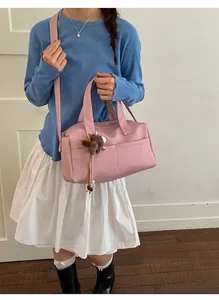 Detailed shot of pink faux leather Boston bag with plush bear charm and crossbody strap