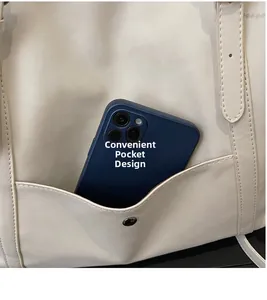 Detail of the front pocket design on a cream tote bag with metal snap and smartphone