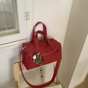 Detail of red pebbled leather bowling bag with brown horse charm on a wooden chair