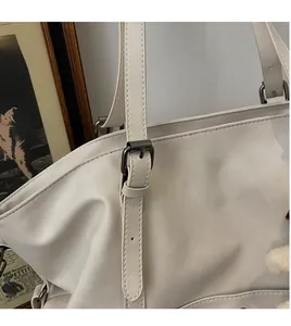 Close-up of adjustable shoulder strap with gunmetal buckle on apricot tote bag