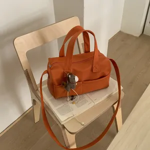 Orange lychee grain leather Boston bag with a cute pony charm and long strap on a chair