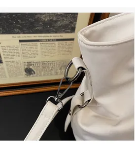 Close-up of high-quality silver metal hardware and textured leather strap on white tote bag