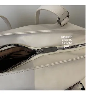 Detail of smooth gunmetal zipper and brown striped lining on off-white tote bag